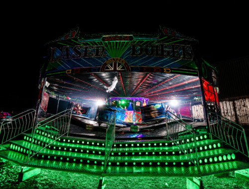 Fairground Rides at SCREAMS! at Thornton Hall Country Park Neon-lit ride glowing green at night during SCREAMS! at Thornton Hall Country Park Halloween event.