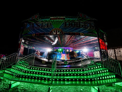 Fairground Rides at SCREAMS! at Thornton Hall Country Park Neon-lit ride glowing green at night during SCREAMS! at Thornton Hall Country Park Halloween event.